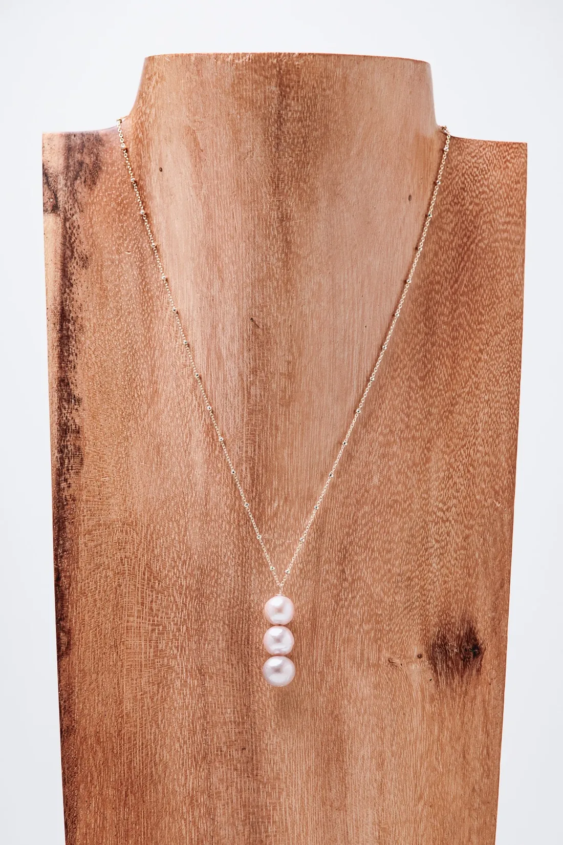 Malia necklace with three pink Edison pearls on the koa wood display